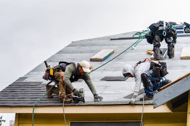 Roofing contractor installing shingles on a house